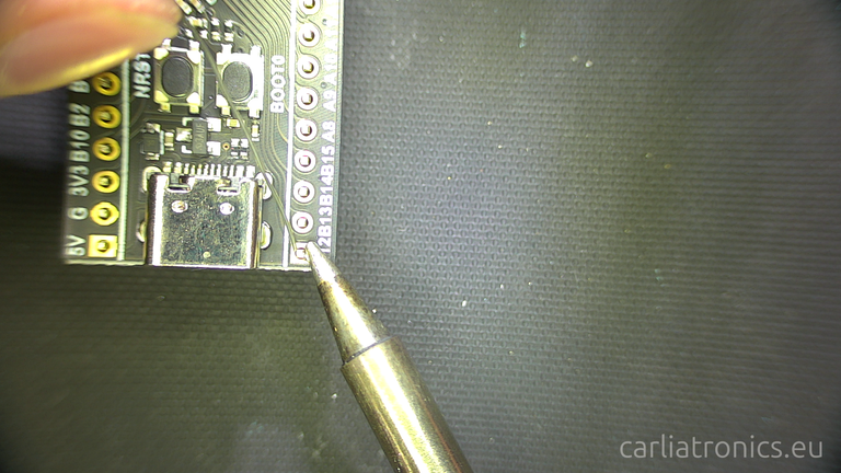 A solder iron tip on a pad with solder wire being added to the joint